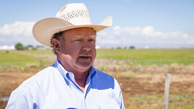 Mr. Guttersen speaks to the camera in a cowboy hat and his fields