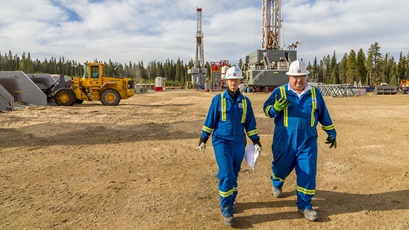 2 employees walking in an oil and gas field